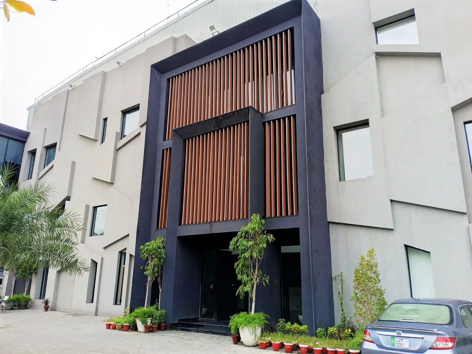 Front view of timber-screened entrance portal and faceted facade, Ambition Apparel, Lahore. LEED Platinum-certified manufacturing facility. Photo: Ambition Apparel / Designers East.